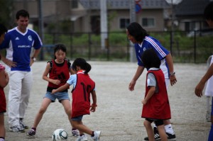 Professional soccer player Tsuyoshi Kitazawa coaches kids in Natori at a NICCO-sponsored event.